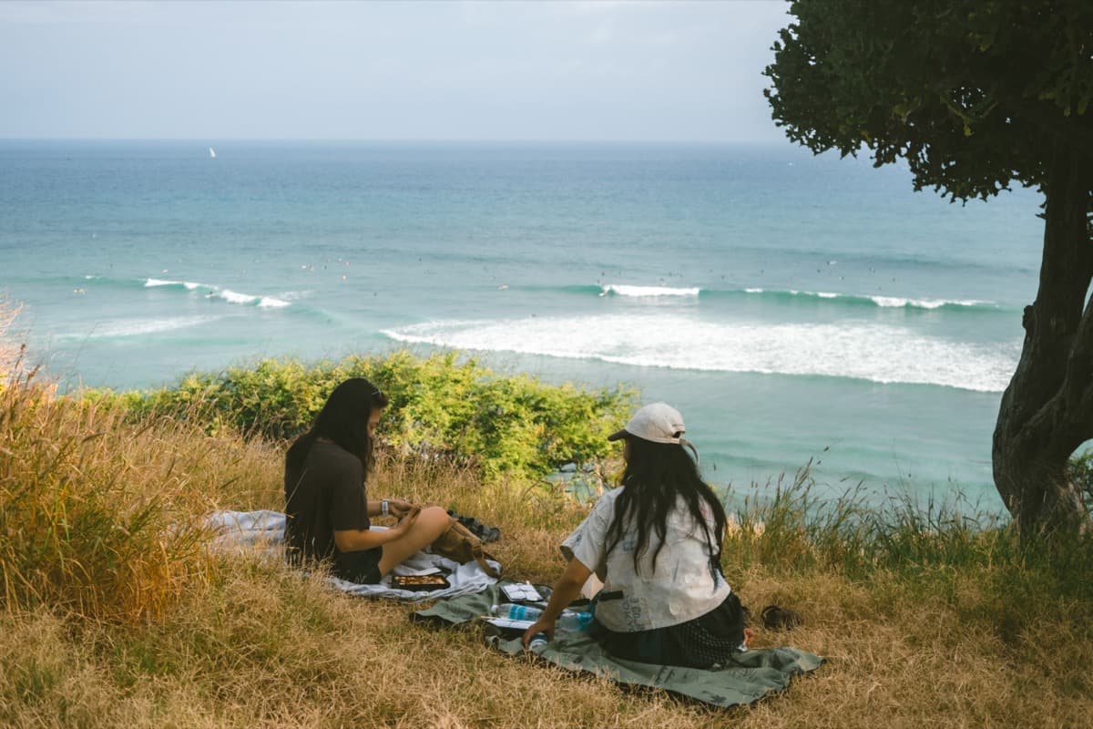 Friends enjoying a clifftop picnic overlooking the ocean
