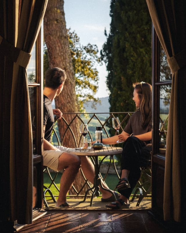 Alice and her husband enjoying wine on a European balcony at golden hour