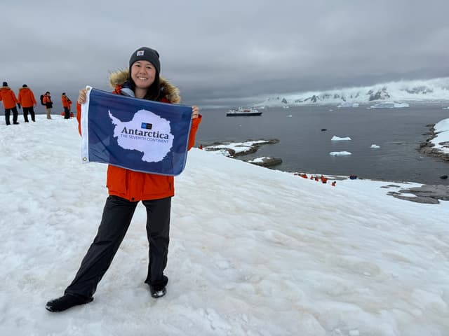 Alice holding an Antarctica flag on the seventh continent